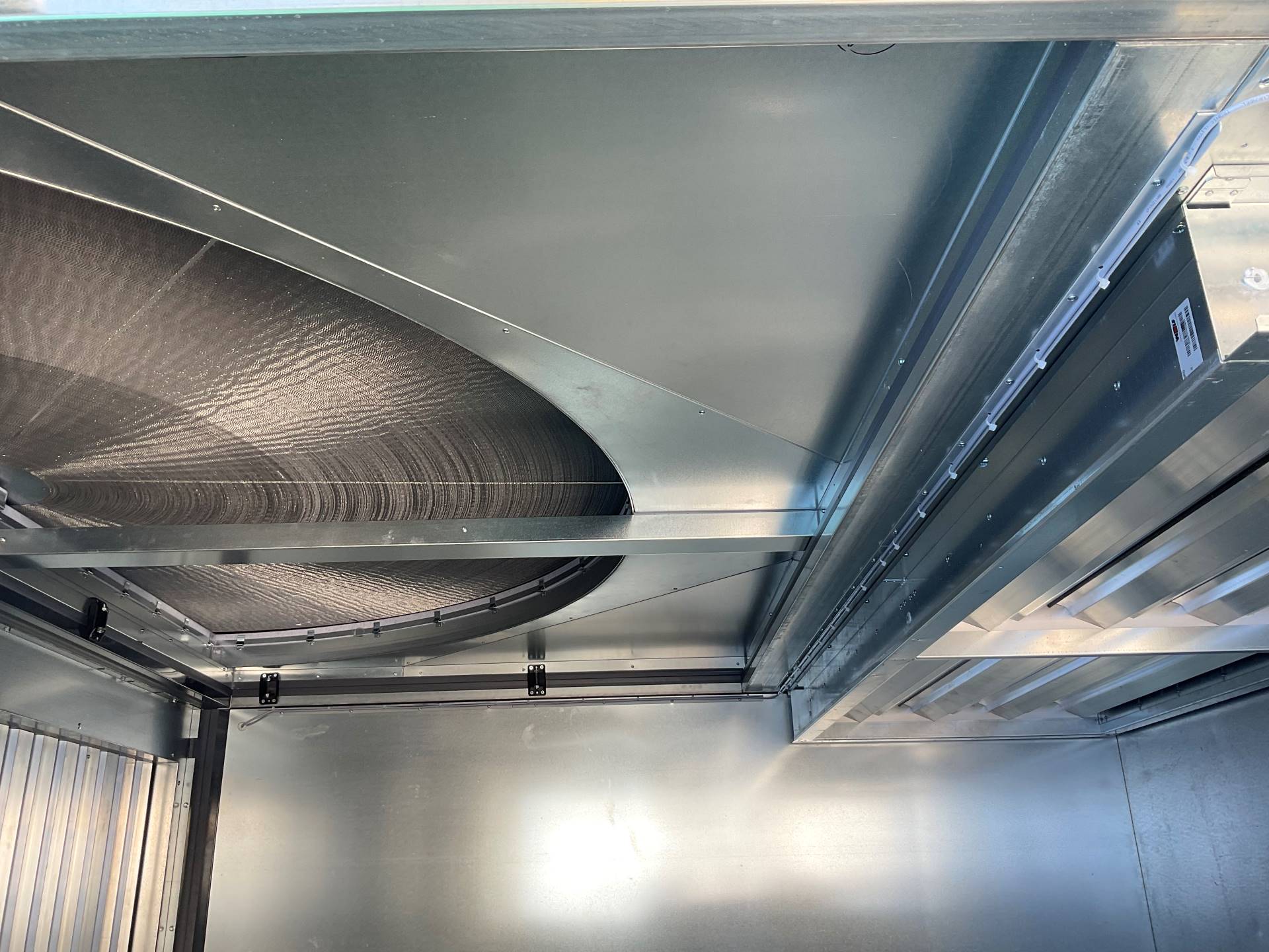 Detailaufnahme eines Wärmetauschers in einer Lüftungsanlage. Sichtbar sind metallische Lamellen und Gehäuseteile, die für die Heizungs-, Lüftungs- und Klimatechnik (HLK) zur effizienten Wärmeübertragung in industriellen Gebäuden eingesetzt werden.